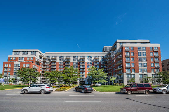 a large apartment building on a city street with cars parked in front
