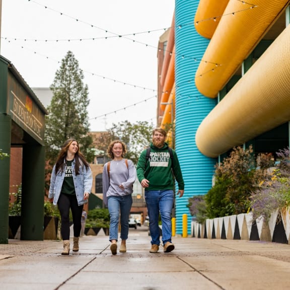 three people walking down a sidewalk in front of a building