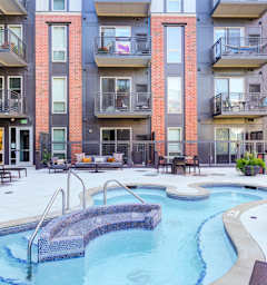 A small pool with a metal railing is surrounded by chairs and tables.