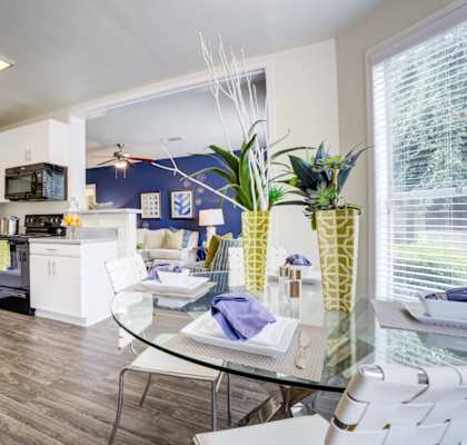 A modern kitchen with a glass table and white chairs.