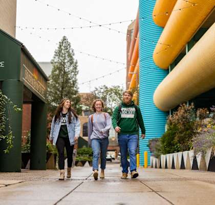 three people walking down a sidewalk in front of a building