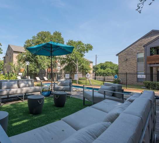 A patio with a white couch and a blue umbrella.
