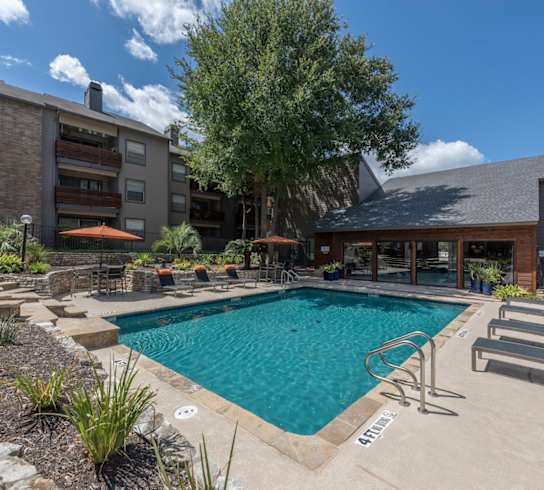 A swimming pool surrounded by lounge chairs and plants.