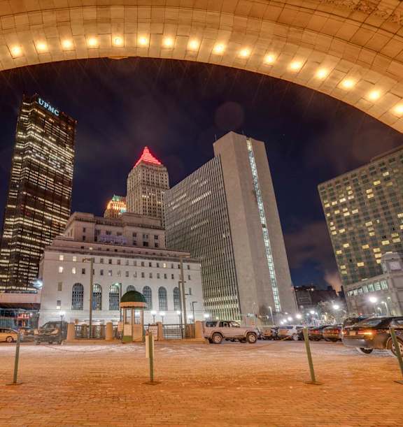 A cityscape at night with a large archway in the foreground. at The Pennsylvanian Apartments, Pittsburgh, Pennsylvania