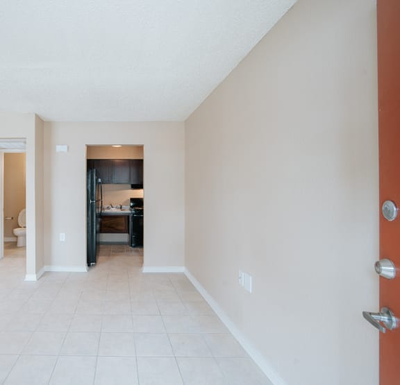 a living room with a tiled floor and a kitchen in the background
