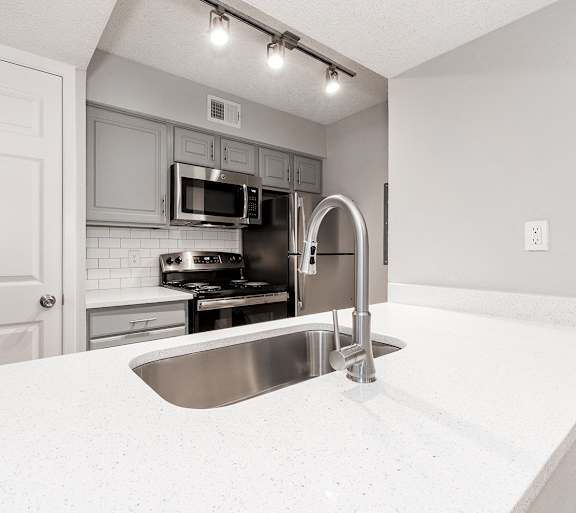 an empty kitchen with stainless steel appliances and white cabinets