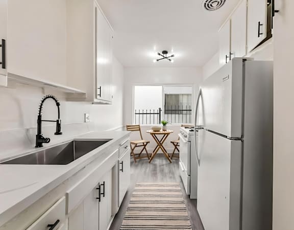 A kitchen with white cabinets and a striped rug on the floor.
