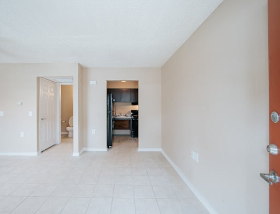 a living room with a tiled floor and a kitchen in the background