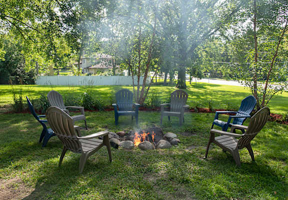 A fire pit surrounded by chairs in a backyard.