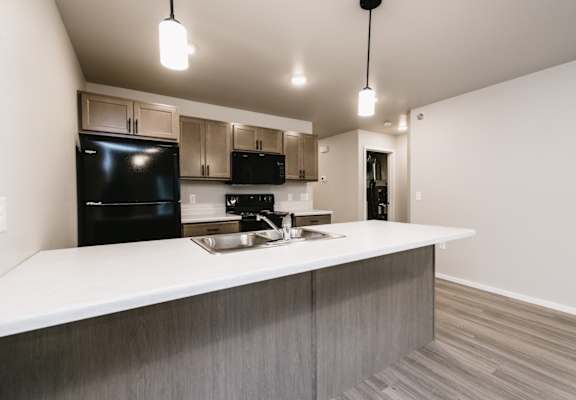 A modern kitchen with a black fridge and stove top oven.