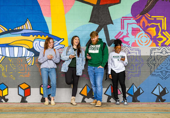 people standing in front of a wall with their cell phones