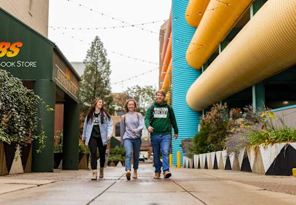 three people walking down a sidewalk in front of a building