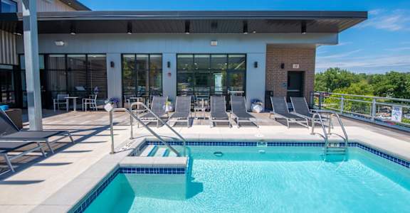 A swimming pool in front of a building with a glass door.at Soll, Des Moines, IA 50312