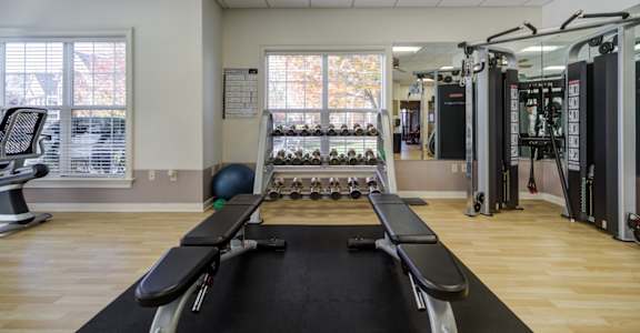 A gym with a row of treadmills on the right and a row of exercise machines on the left at The Crest at Elm Tree, Mount Joy, PA