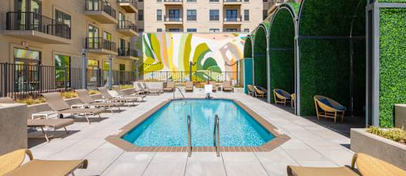 A pool surrounded by lounge chairs and umbrellas.