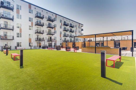 an outdoor area with benches and tables in front of an apartment building