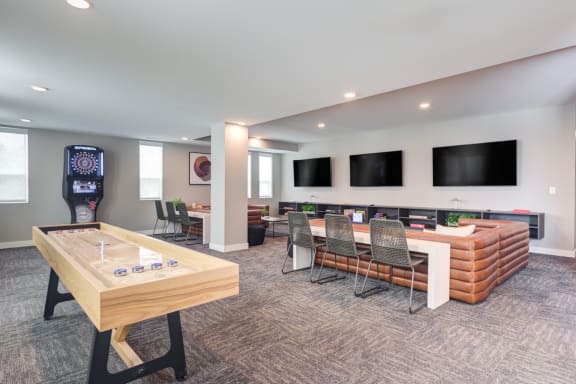 a recreation room with a foosball table and flat screen televisions