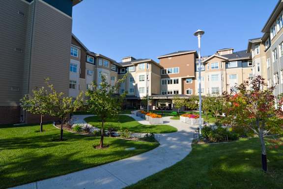 A sunny day at a residential complex with a pathway and greenery.