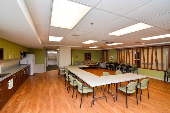 A large white table surrounded by chairs in a room with wooden floors.
