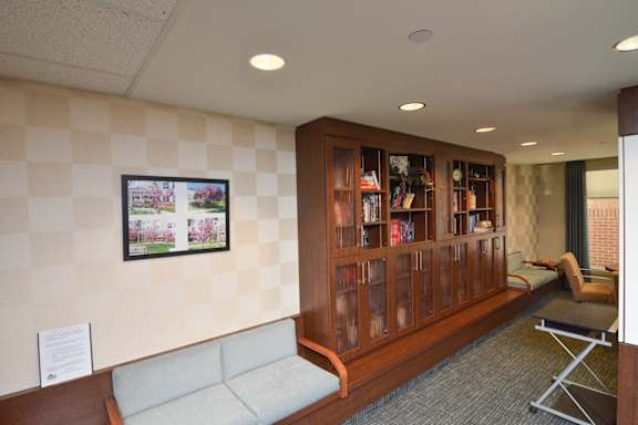A waiting room with a sofa, a chair, and a bookshelf.