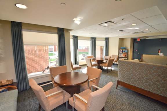 A room with a table and chairs in front of a window.