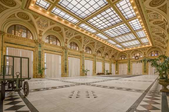 A large room with a checkered floor and a carriage in the foreground. at The Pennsylvanian Apartments, Pittsburgh, Pennsylvania