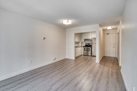 A spacious room with a kitchenette in the background.