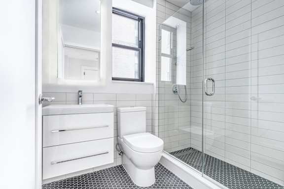 Bright tiled bathrooms with large backlit designer mirror, Hans Grohe chrome fixtures and Villeroy & Boch vanity