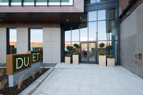 The entrance to a building with a sign that reads "DUET" in front of it.