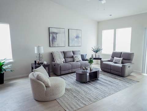 A living room with a grey sofa, a grey armchair, and a grey coffee table.