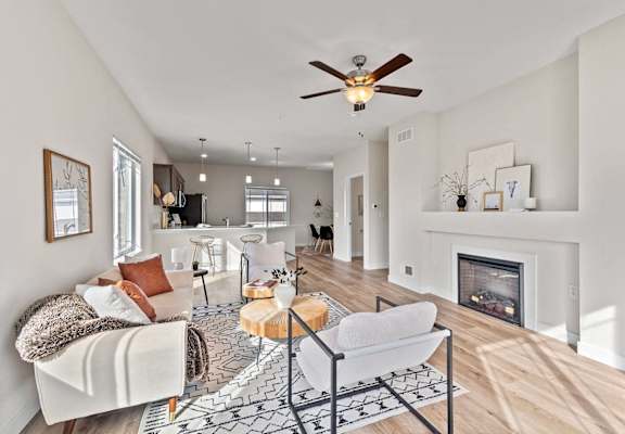 an open living room with a fireplace and a ceiling fan at The Residences Apartments at Bear Tree | DeForest, WI, Wisconsin
