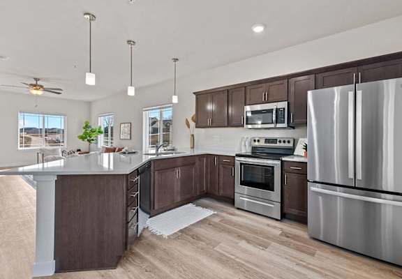 a kitchen with stainless steel appliances and wooden cabinets at The Residences Apartments at Bear Tree | DeForest, WI, Wisconsin, 53532