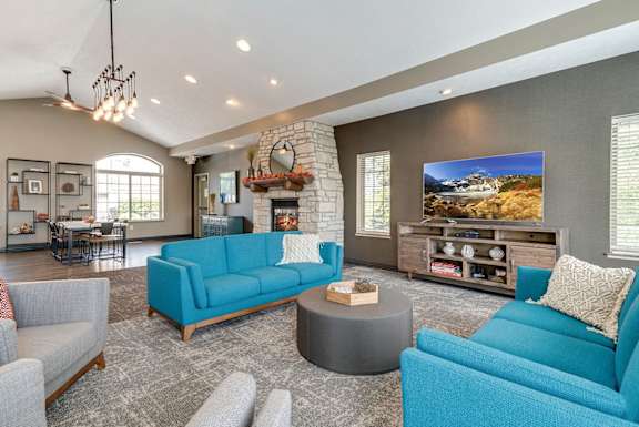 a clubhouse living room with blue couches and a fireplace