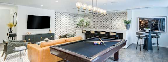 A pool table is in the middle of a room with a couch and a television.