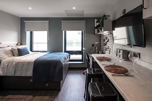A modern bedroom with a large bed and a kitchenette area.