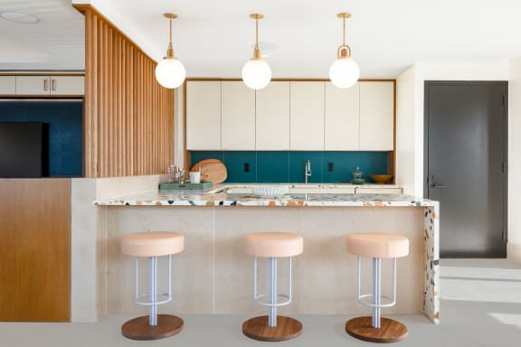 a kitchen with pink stools and white cabinets and a counter at The Grace and Reva, Virginia, 22202