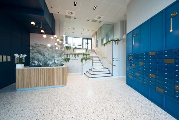 A reception area with a wooden desk and a staircase with a green plant on it.