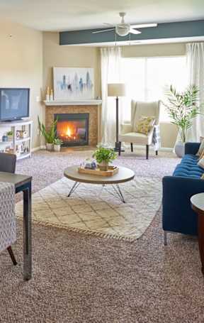 A living room with a fireplace and a dining table set for six. at The Winhall of Williams Pointe Apartments, Waukee