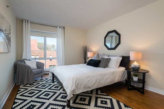 a bedroom with a bed and a chair and a window