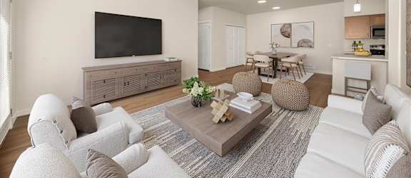 A living room with a white couch, a coffee table, and a television.