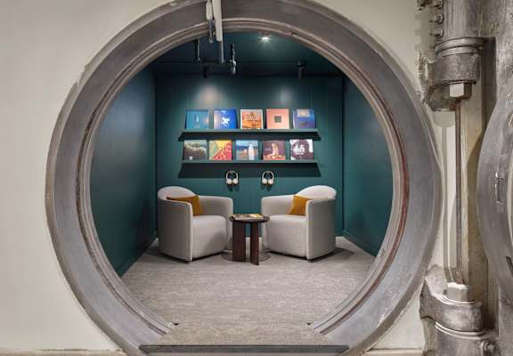 A room with a circular opening in the wall and two chairs.