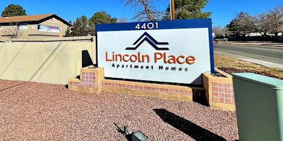 A sign for Lincoln Place Apartment Homes is displayed in front of a building.
