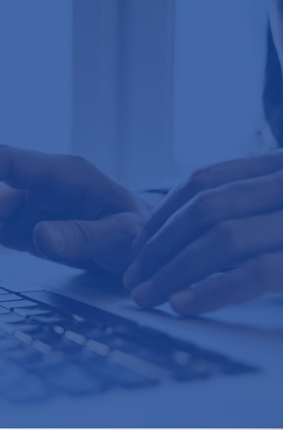 A person's hands are typing on a laptop keyboard.