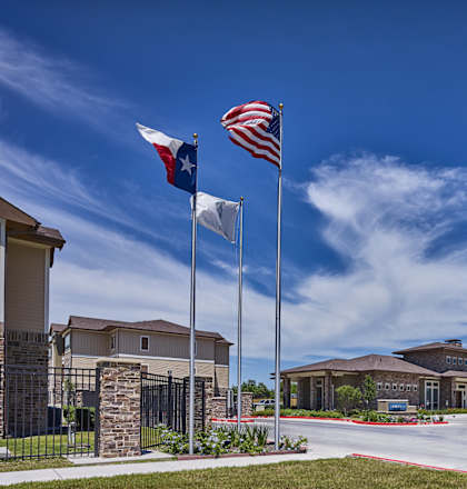 A building with a Texas flag and an American flag on flagpoles in front of it.