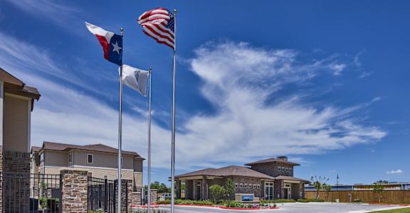 A building with a Texas flag and an American flag on flagpoles in front of it.