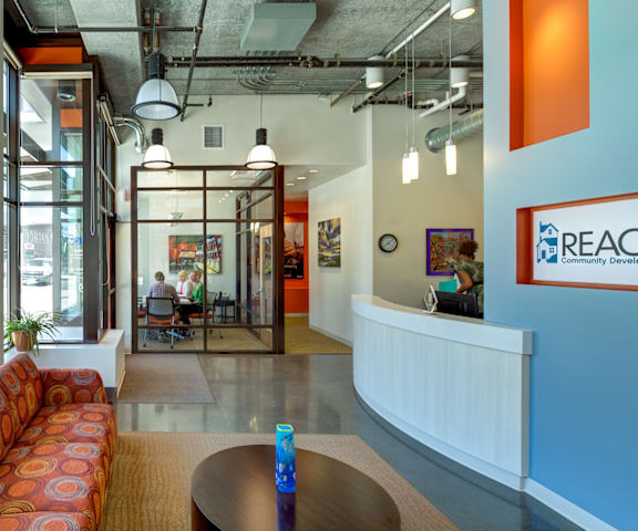 A brightly lit office space with a reception desk and a sofa.