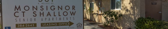 A sign for Monsignor Ct Shallow Senior Apartments stands in front of a building.