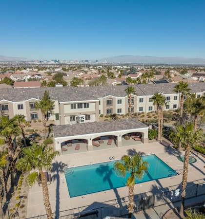 A large house with a pool surrounded by palm trees.