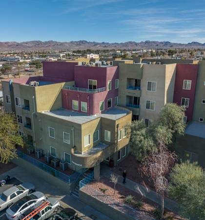 Apartment complex with a parking lot in front.