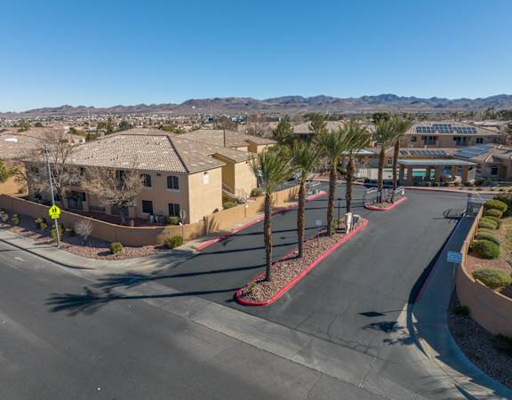 A street view of a residential area with houses and palm trees.